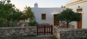 a white house with a stone wall and a fence at Traditional house in Asfendiou in Kos