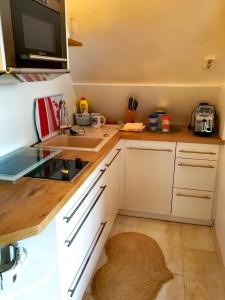 eine kleine Küche mit weißen Schränken und einem Waschbecken in der Unterkunft Rosenblick in Zingst