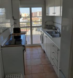 a kitchen with white cabinets and a sink and a window at APARTAMENTO PLAYA DE REGLA, Chipiona, primera linea in Chipiona