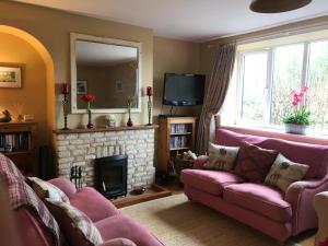 a living room with a pink couch and a fireplace at Rose Cottage, 4 The Hill in Burford