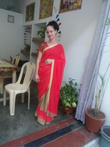 a woman in a red dress standing in a room at Namaste Homestay in Khajurāho