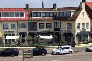 een groep auto's geparkeerd voor een gebouw bij Hotel Anna in Zandvoort