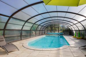 an indoor swimming pool with a glass ceiling at Au Temps Retrouvé in Courcelles