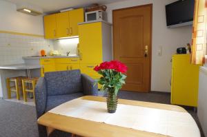 een vaas met rode bloemen op een tafel in een keuken bij Gästehaus Gaens - Ferienwohnung in Schirgiswalde