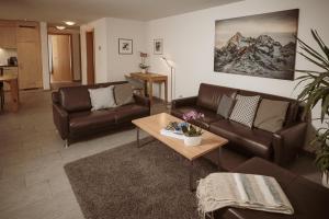 una sala de estar con 2 sofás de cuero y una mesa. en Haus Mischabel, en Zermatt