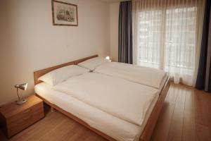 a bedroom with a white bed with a window at Haus Mischabel in Zermatt