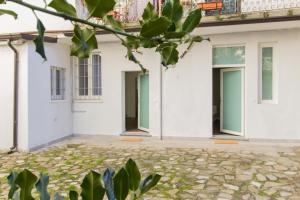 an empty courtyard of a white building with green doors at Malta Guest House in Piacenza