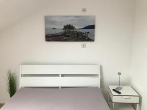 a white bedroom with a bed and a picture on the wall at Ferienapartment Resi in Willingen