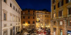 una calle de la ciudad por la noche con coches estacionados entre edificios en Tula Inn, en Roma