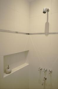a white tiled bathroom with a shower and a sink at Casa Bordó Salta in Salta