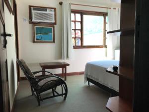 a bedroom with a bed and a chair and a window at Pousada Agua Viva in Abraão