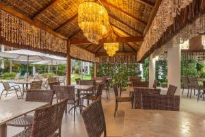 a restaurant with tables and chairs and a chandelier at Hotel Coral Beach in Tamandaré