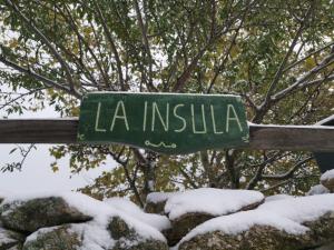a green sign that says la insulinosa in the snow at Casa Rural la Insula in Santa María de la Alameda