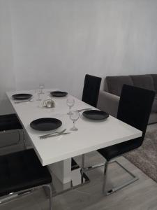 una mesa blanca con 4 sillas y copas de vino. en Luxury Daniel Apartament Residence Militari, en Roşu