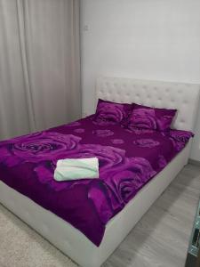 Una cama con sábanas moradas y una toalla blanca. en Luxury Daniel Apartament Residence Militari, en Roşu