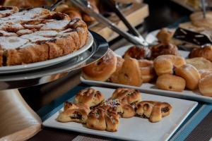 a table topped with plates of pastries and pies at Hotel Baia Di Venere in San Vito lo Capo
