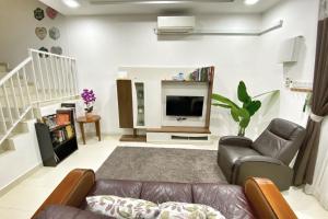 ein Wohnzimmer mit einem Sofa und einem TV in der Unterkunft Teratak Persona Homestay. 4 rooms double storey terrace in Kuantan City. in Kuantan