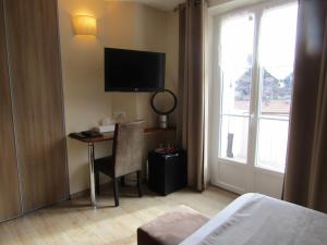a hotel room with a desk with a television and a bed at Fifi Moulin in Serres
