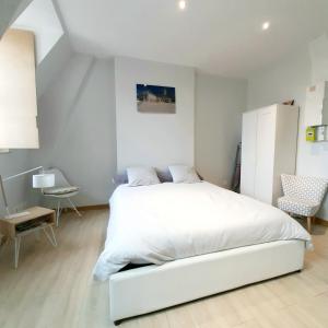 - une chambre blanche avec un lit blanc et une chaise dans l'établissement Studio Jean LEBELIN, à Dijon