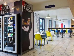 um restaurante com um frigorífico de serviço de refrigerantes e mesas e cadeiras em ibis budget Chilly-Mazarin Les Champarts em Chilly-Mazarin