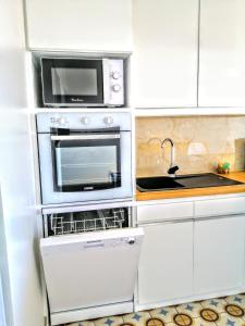 a white kitchen with a microwave and a sink at Bélavue & SPA Privé, avec vue panoramique sur mer, jardin créole paysager, jacuzzi privé in Bouillante