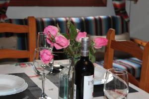una botella de vino sentada en una mesa con rosas rosas en Apartamentos Rurales Rosendo: El Tomillo, en Capileira
