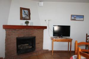 a living room with a brick fireplace with a tv at Apartamentos Rurales Rosendo: El Tomillo in Capileira