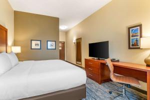 a hotel room with a bed and a desk with a television at Comfort Inn & Suites West Des Moines in West Des Moines