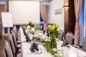a row of tables with yellow roses in a vase at Nowa - Ski SPA Hotel in Karpacz