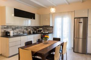 La casa di Eleni في أكارافي: مطبخ مع طاولة مع كراسي وثلاجة
