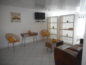 a living room with a couch and chairs and a tv at Chez Isa et JP in Soulac-sur-Mer