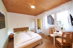um quarto com uma cama, uma mesa e uma janela em Gästehaus Achenbach em Wonsheim