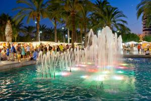 a fountain in a pool with people standing around it at Apartamentos Bon Lloc in Santa Eularia des Riu