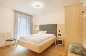 1 dormitorio con 1 cama y 1 silla en Ariala - Mountain Holiday Home en Falzes