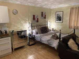 a bedroom with a bed and a couch and a clock at Southernwood - Studio 2 in Didcot