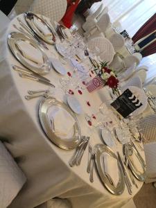 un tavolo bianco con piatti e utensili d'argento di Hotel Columbus sul Lago a Bolsena