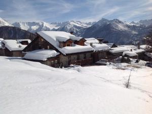 a house covered in snow with mountains in the background at Agriturismo il Fiocco in Cesana Torinese