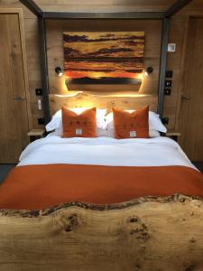 1 dormitorio con 1 cama grande de madera con almohadas de color naranja en Ardcana, en Breakish