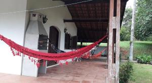 een rode hangmat die buiten een huis hangt bij Chácara Santista in Serra Negra