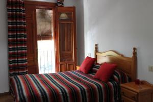 a bedroom with a bed with a striped blanket and a window at Apartamentos Rurales Rosendo: El Jazmin in Capileira