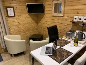 a dining room with a table with a laptop on it at Southernwood - Garden Lodge 9 in Didcot