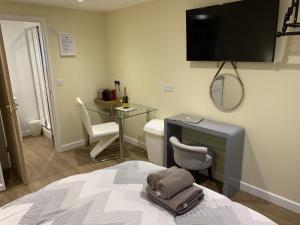 a bedroom with a bed with a desk and a toilet at Southernwood - Garden Lodge 10 in Didcot