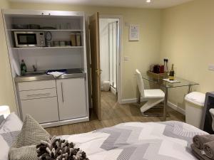 a bedroom with a bed and a desk and a kitchen at Southernwood - Garden Lodge 11 in Didcot