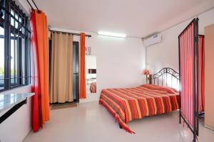 Schlafzimmer mit einem Bett mit orangefarbenen Vorhängen und einem Fenster in der Unterkunft Cosy Studio #3 - Pereybere in Pereybere