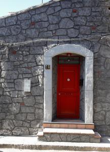 una puerta roja en una pared de piedra con una puerta roja en ZazzamitaHouse, en Catania