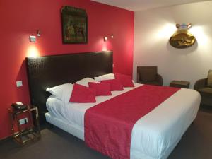 una camera da letto con un grande letto con pareti rosse di Hôtel de La Croix d'Or ad Avranches