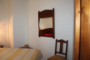 1 dormitorio con cama y espejo en la pared en Apartamentos Rurales Rosendo: La Orquídea, en Capileira