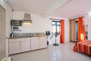 eine Küche mit weißen Wänden und orangefarbenen Vorhängen in einem Zimmer in der Unterkunft Cosy Studio #3 - Pereybere in Pereybere