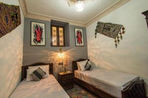 een slaapkamer met twee bedden en een lamp aan de muur bij Dar Zerbtana Apartment in Fès