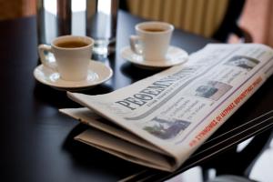 a newspaper on a table with two cups of coffee at Achillion Palace in Rethymno
